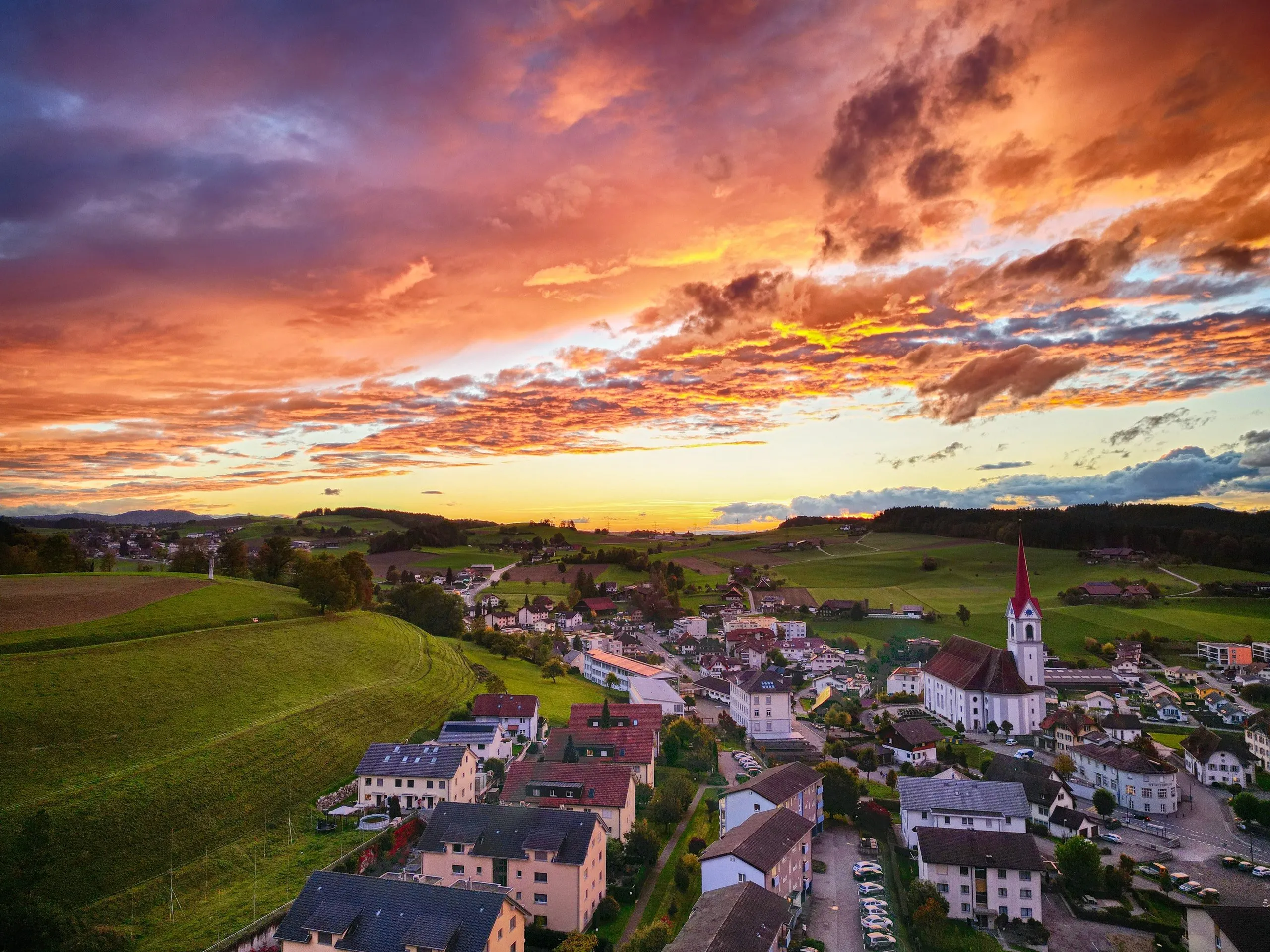 Pfaffnau im Abendrot: das Dorf mit Kirchturm, eingebettet in die Hügel des Luzerner Hinterlands